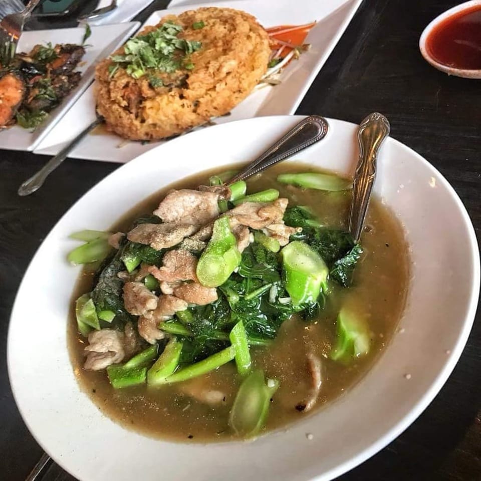 A bowl of Wat Dong Moon Lek Noodle's Thai dish with pork, green vegetables, and gravy.